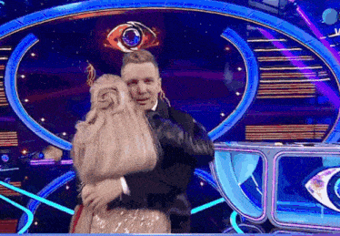 a man and woman are hugging in front of a big eye