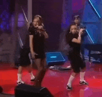 a group of people are dancing on a stage in a dark room .