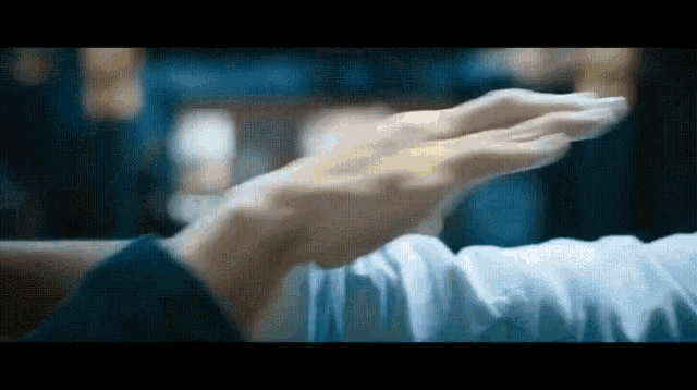 a close up of a person 's hands reaching out towards each other in a blurry photo .