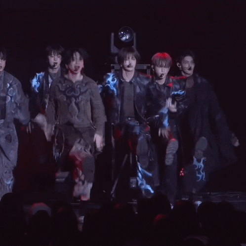 a group of people are dancing on a stage and one of them is wearing a jacket that says ' ao ' on it