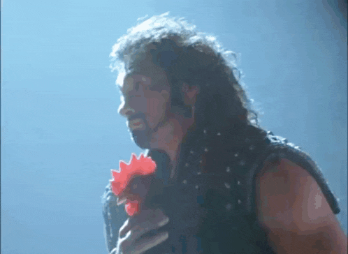 a man with long hair and a beard is holding a red rooster