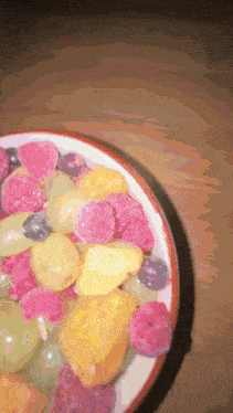 a bowl of fruit including grapes raspberries and pineapple