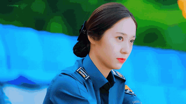 a woman in a police uniform looks at the camera with a blue background