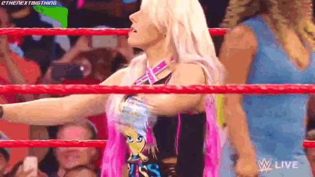 a female wrestler is standing in a wrestling ring with her arms outstretched .