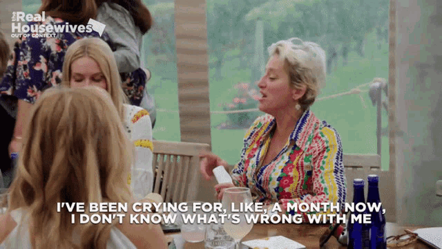 a group of women are sitting at a table and one of them is saying " i 've been crying for "