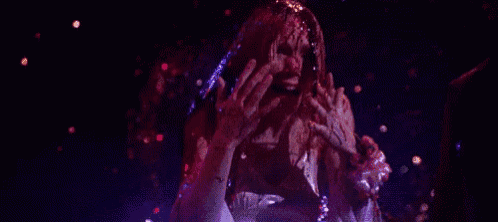 a woman is standing in a dark room with confetti falling around her .