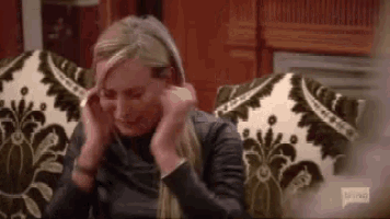 a woman is sitting in a chair covering her ears