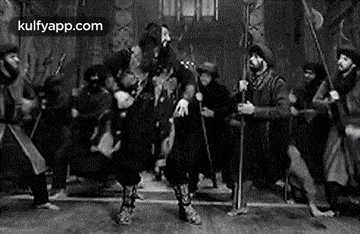 a black and white photo of a group of men dancing in a room .