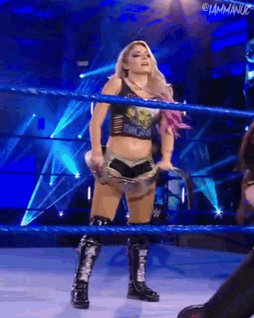 a female wrestler is standing in a wrestling ring holding a rope .