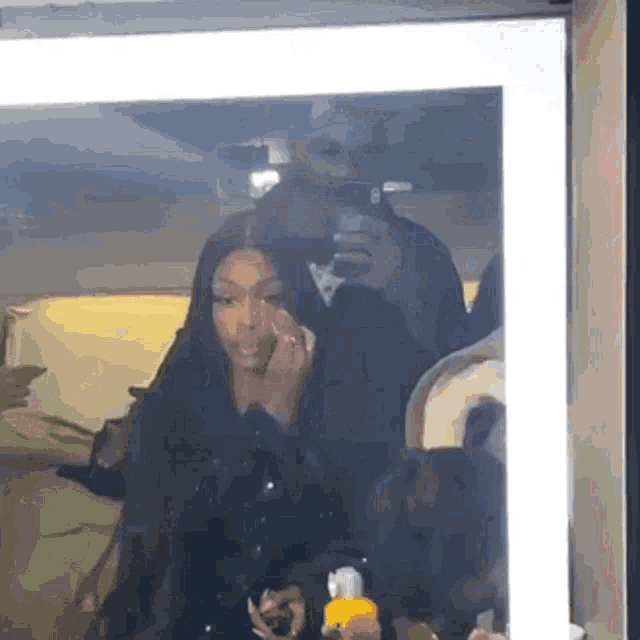 a woman is taking a selfie in front of a mirror while a man looks on .