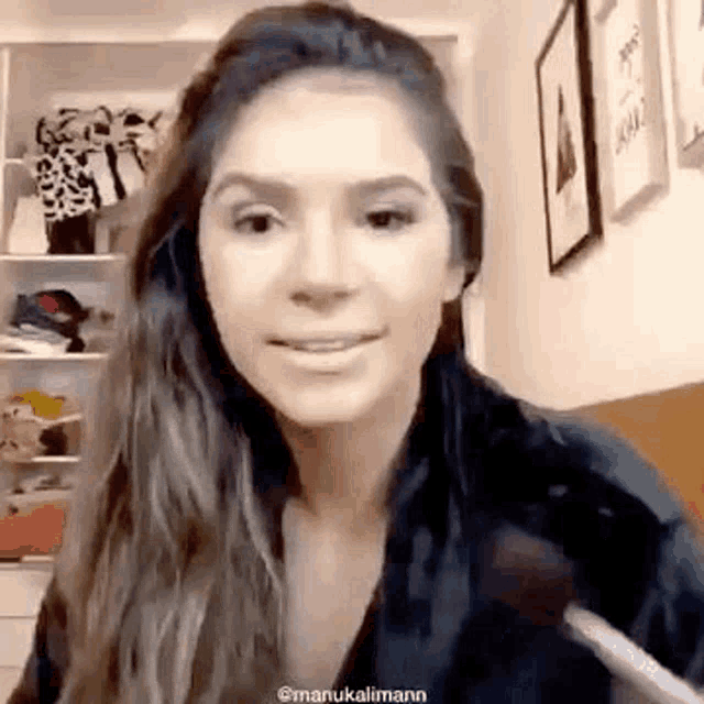 a woman is holding a brush in her hand and smiling while looking at the camera .
