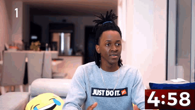 a man wearing a sweatshirt that says just do it sits on a couch