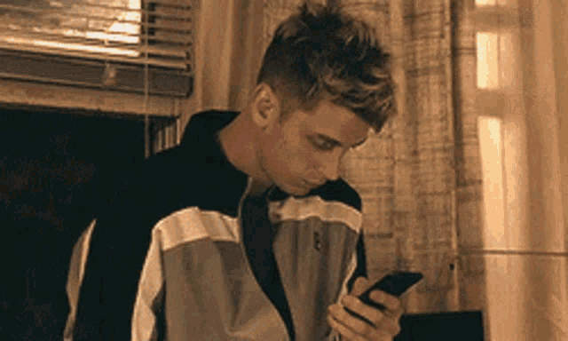 a young man is looking at his cell phone