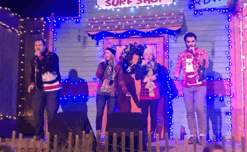 a group of people singing in front of a sign that says surf shop