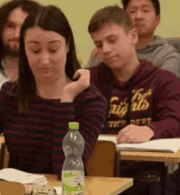 a group of students are sitting at desks in a classroom with a bottle of water in front of them ..