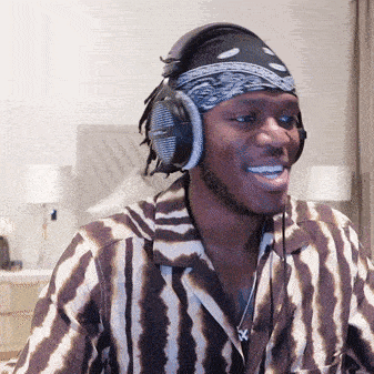 a man wearing headphones and a bandana smiles for the camera