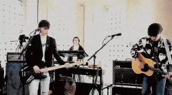 a man is playing a guitar and a man is playing a keyboard on stage .