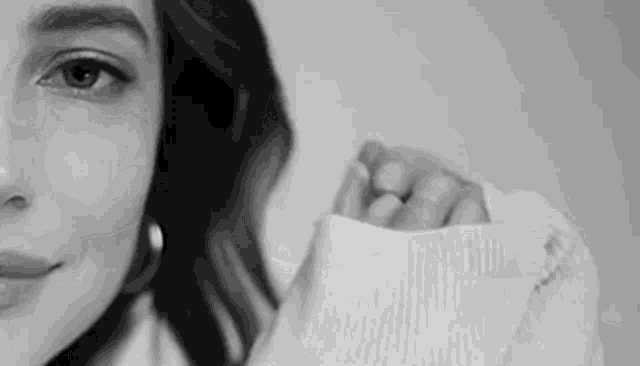 a black and white photo of a woman wearing a sweater .