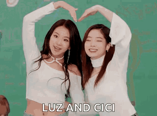 two girls are making a heart shape with their hands and the words luz and cici are written below them .
