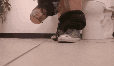 a person sitting on a toilet with their pants down and converse shoes on