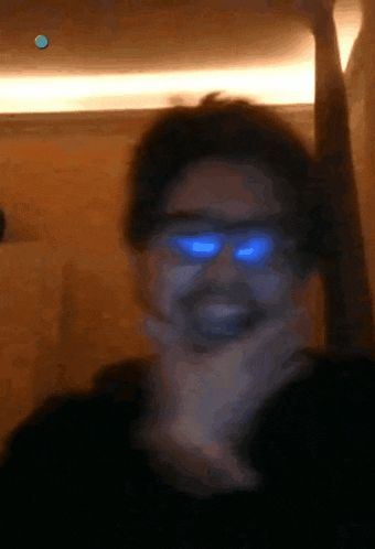 a blurry picture of a man wearing glasses with blue lenses