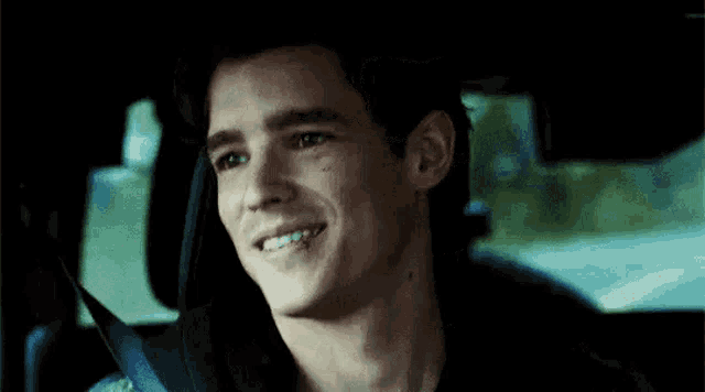 a man is sitting in the back seat of a car with his eyes closed and smiling .