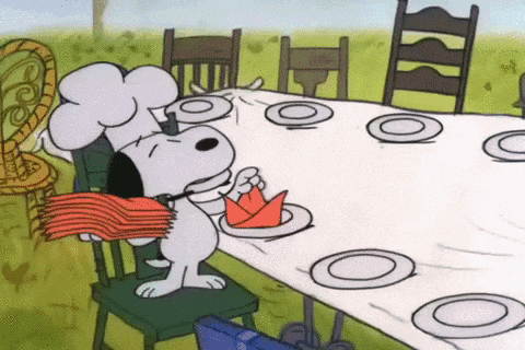 a cartoon of snoopy wearing a chef 's hat sitting at a table