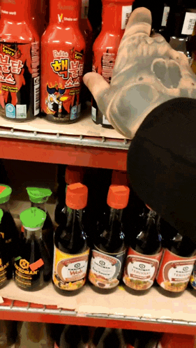 several bottles of sauce are on a shelf including a bottle that says ' korean ' on it