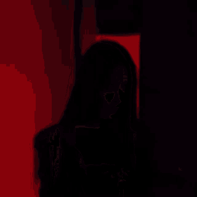 a woman with long black hair and red lipstick is standing in a dark room .