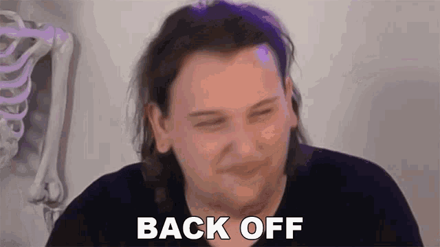 a man is making a funny face and saying back off .
