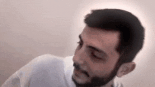a man with a beard wearing a white shirt is looking at the camera .