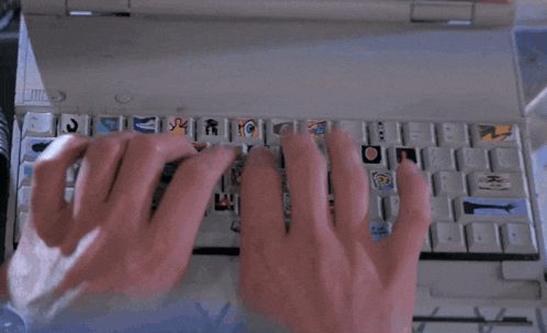 a person typing on a keyboard with stickers on the keys