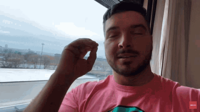 a man wearing a pink shirt with the word deluxe on the bottom