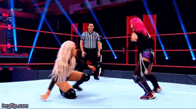 two women are wrestling in a ring with a referee watching