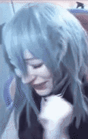 a woman wearing a blue wig and a black shirt is making a funny face .