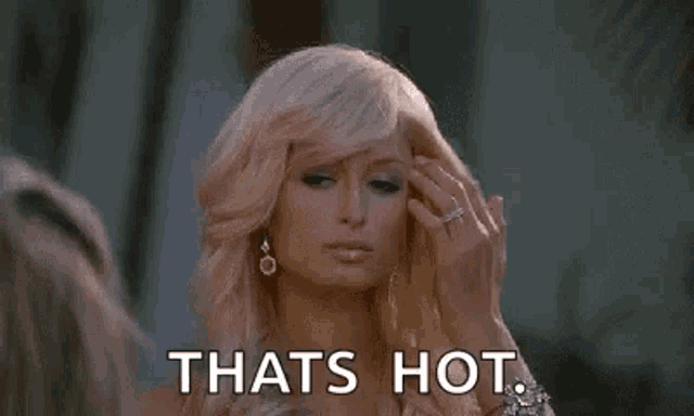 a woman is standing in front of a mirror and saying `` that 's hot '' .