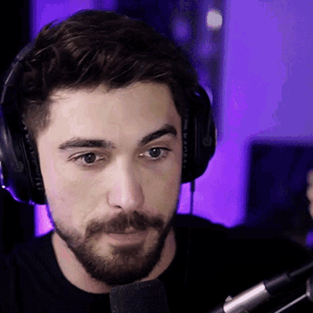 a man with a beard is wearing headphones and looking at a microphone