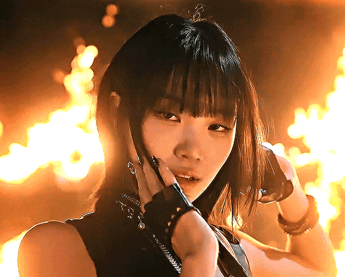 a woman with bangs is standing in front of fire