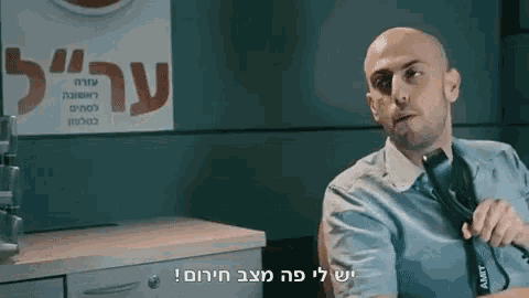 a bald man is sitting in front of a sign that says ' aamt ' on it