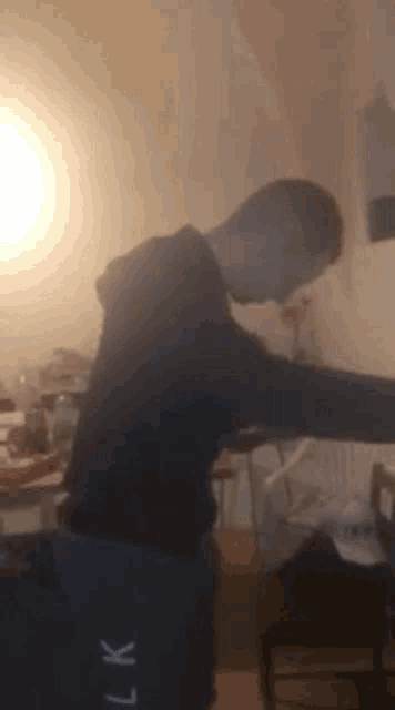 a man in a black hoodie is standing in a room with smoke coming out of his mouth .