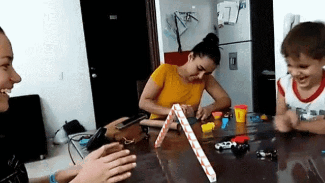 a group of people are sitting around a table playing with play dough .