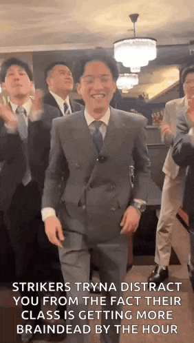 a group of men in suits are dancing together in a room .
