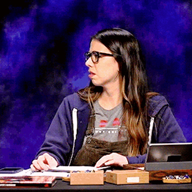 a woman wearing glasses is sitting at a table