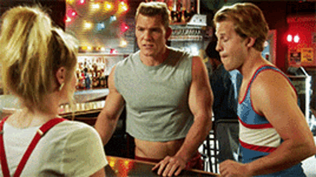a man in a crop top talks to two other men