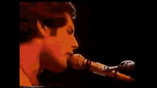 a close up of a man singing into a microphone in a dark room .