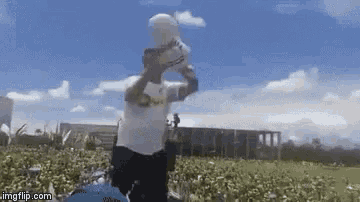 a man in a white shirt is standing in a field holding a white object in his hand .