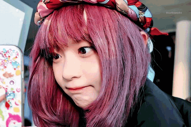 a girl with pink hair and a scarf around her head is making a funny face