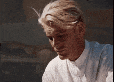 a man in a white shirt looks down at something