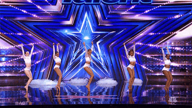 a group of dancers are dancing on a stage in front of a star .