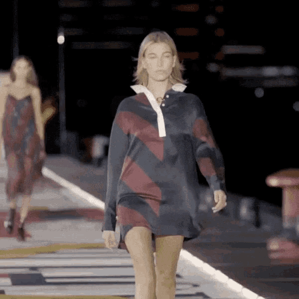 a model walks down a runway wearing a striped shirt dress